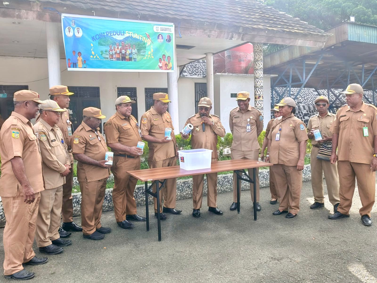 Bupati Jayapura, Dr. Yunus Wonda, S.H., M.H., didampingi Plt. Sekda Kabupaten Jayapura, Dr. Yusup Yambeyabdi, S.T., M.T., dan sejumlah kepala perangkat daerah sedang mengeluarkan koin dari dalam celengan yang terkumpul dari setiap OPD usia Apel Rutin ASN di Lapangan Apel Gunung Merah Sentani. Senin (04/05/2026)